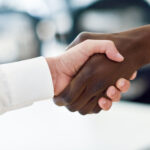 Our Projects Black businessman shaking hands with a caucasian one wearing suit in an office. Close-up shot