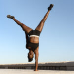 Our Projects Athletic woman doing hand standing on beach. Multiracial woman at the seaside practicing yoga, training balance exercise concept lifestyle