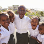Our Projects Young African schoolgirls in playground smiling to camera